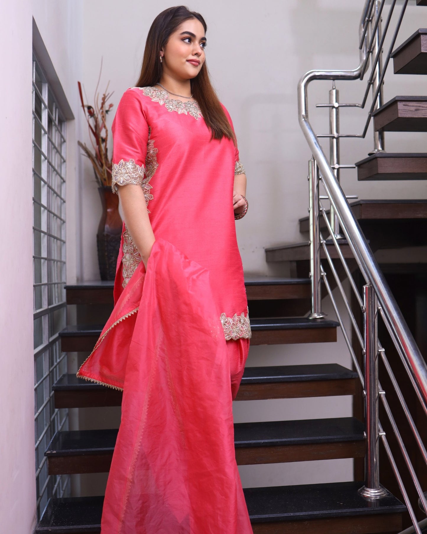 Woman in a pink saree standing on a staircase