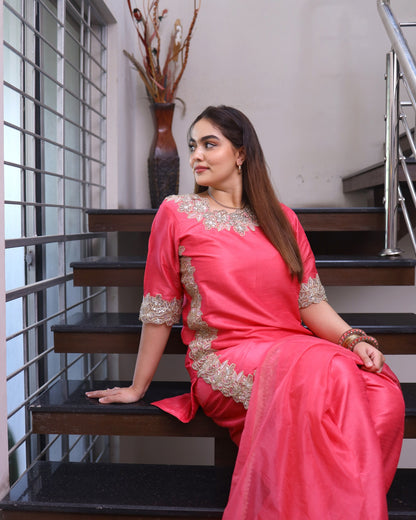 Woman in a pink saree with gold embroidery sitting on stairs.