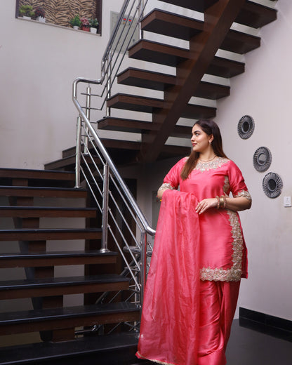 Woman in a pink saree standing in front of a staircase