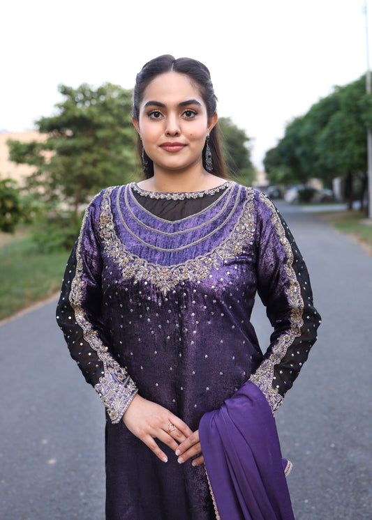 Woman in a purple traditional outfit standing on a road with greenery in the background