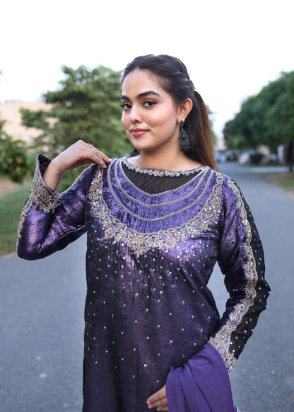 Woman wearing a purple and black embroidered traditional outfit outdoors.