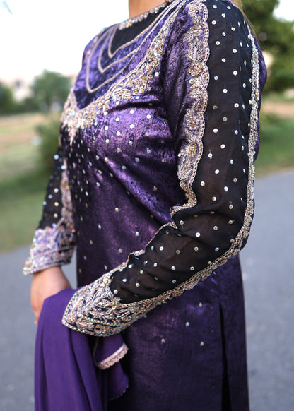 Purple traditional outfit with intricate silver embroidery on a blurred outdoor background