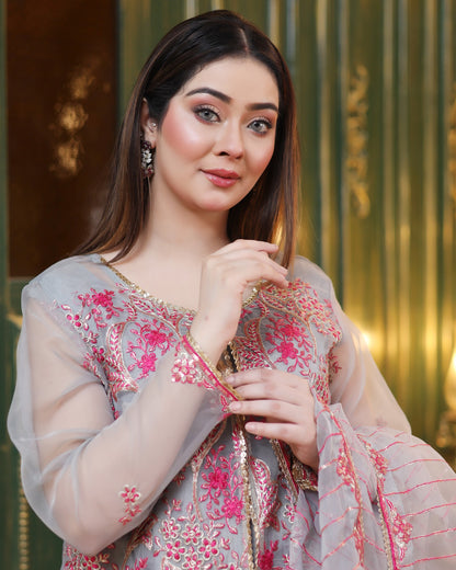 Woman in a traditional outfit with floral patterns against a decorative background