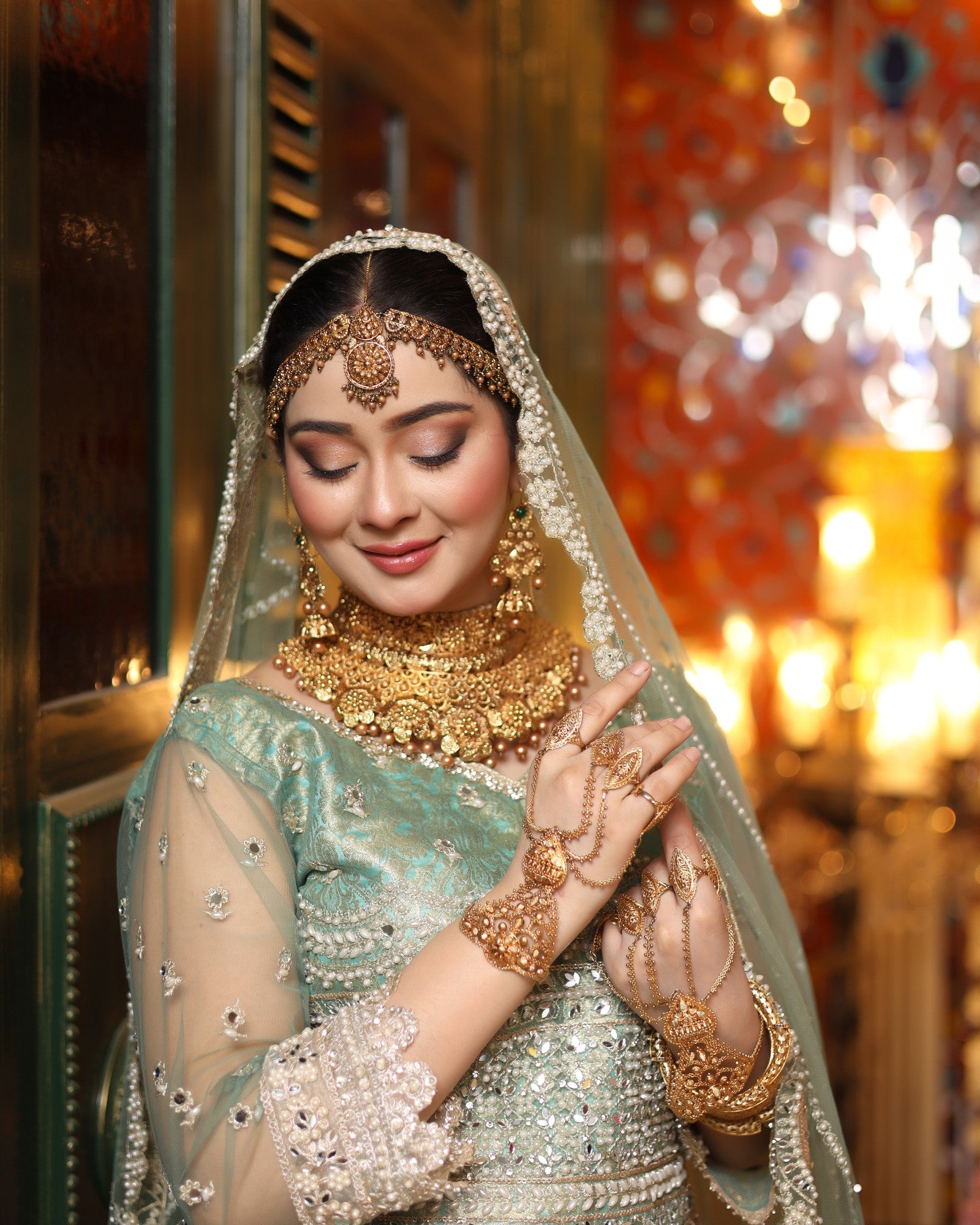Woman in traditional bridal attire with jewelry and a veil, set against a warm-toned background