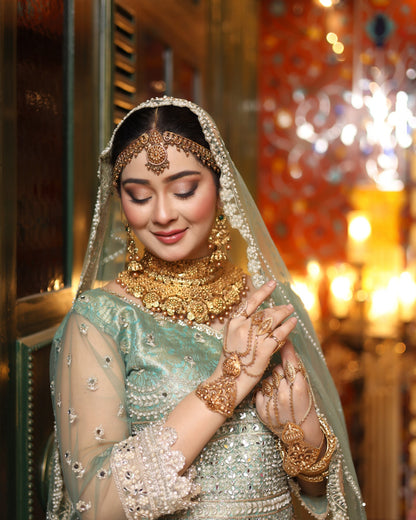 Woman in traditional bridal attire with jewelry and a veil, set against a warm-toned background