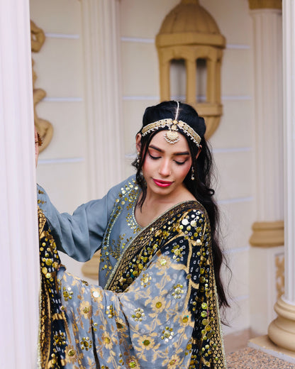 Woman in traditional attire with intricate designs in a decorated interior setting