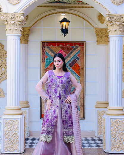 Woman in a purple traditional outfit standing in an ornate interior setting.