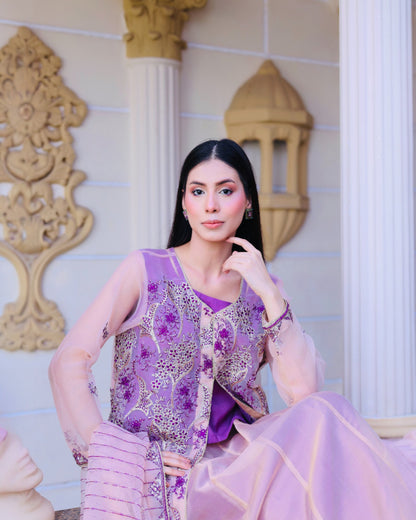 Woman in a purple traditional outfit sitting in an ornate room.