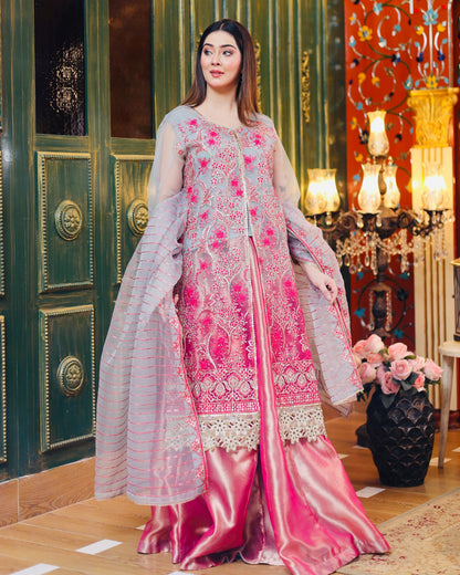 Woman in a pink and white embroidered traditional outfit standing in an ornate room.
