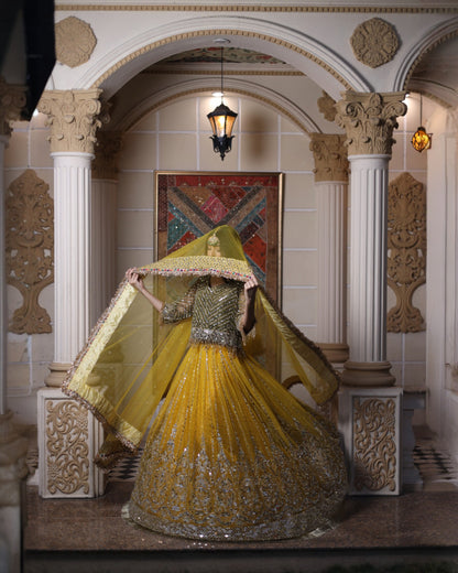 Woman in a yellow and silver traditional outfit standing in an ornate room.