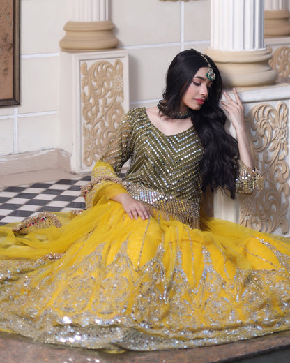 Woman in a yellow and gold traditional outfit sitting on a decorative floor.