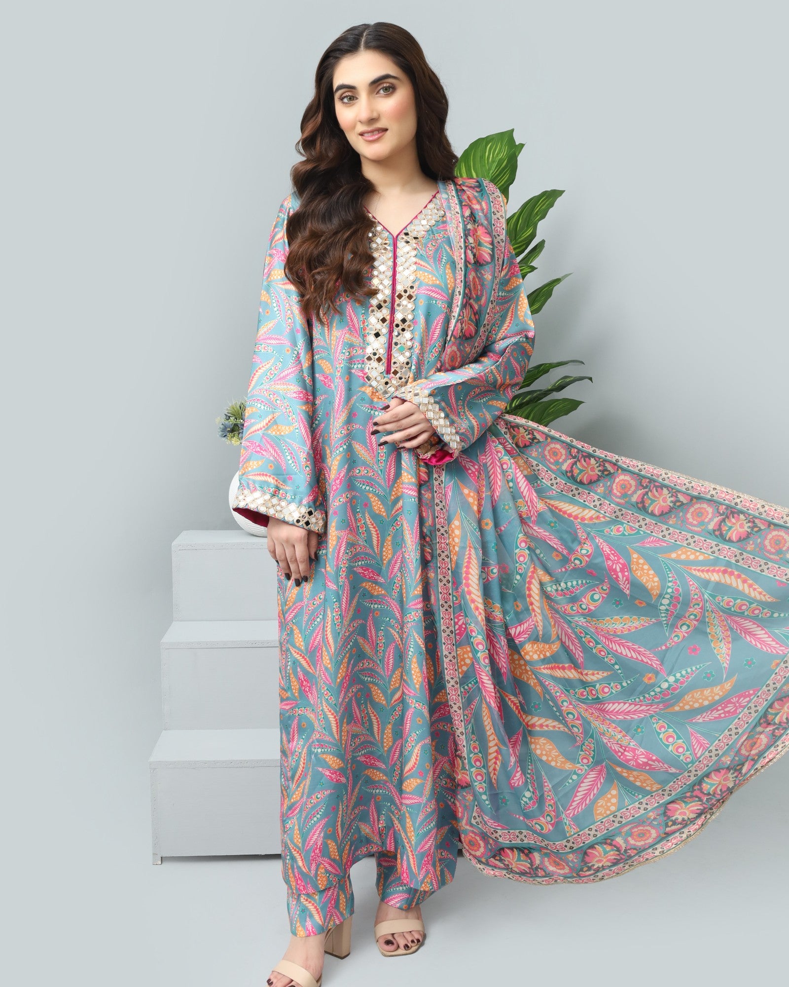 Woman wearing a colorful traditional outfit with a patterned dupatta on a light gray background