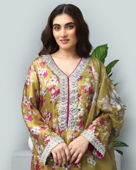 Woman wearing a floral and embroidered traditional outfit with a plant in the background