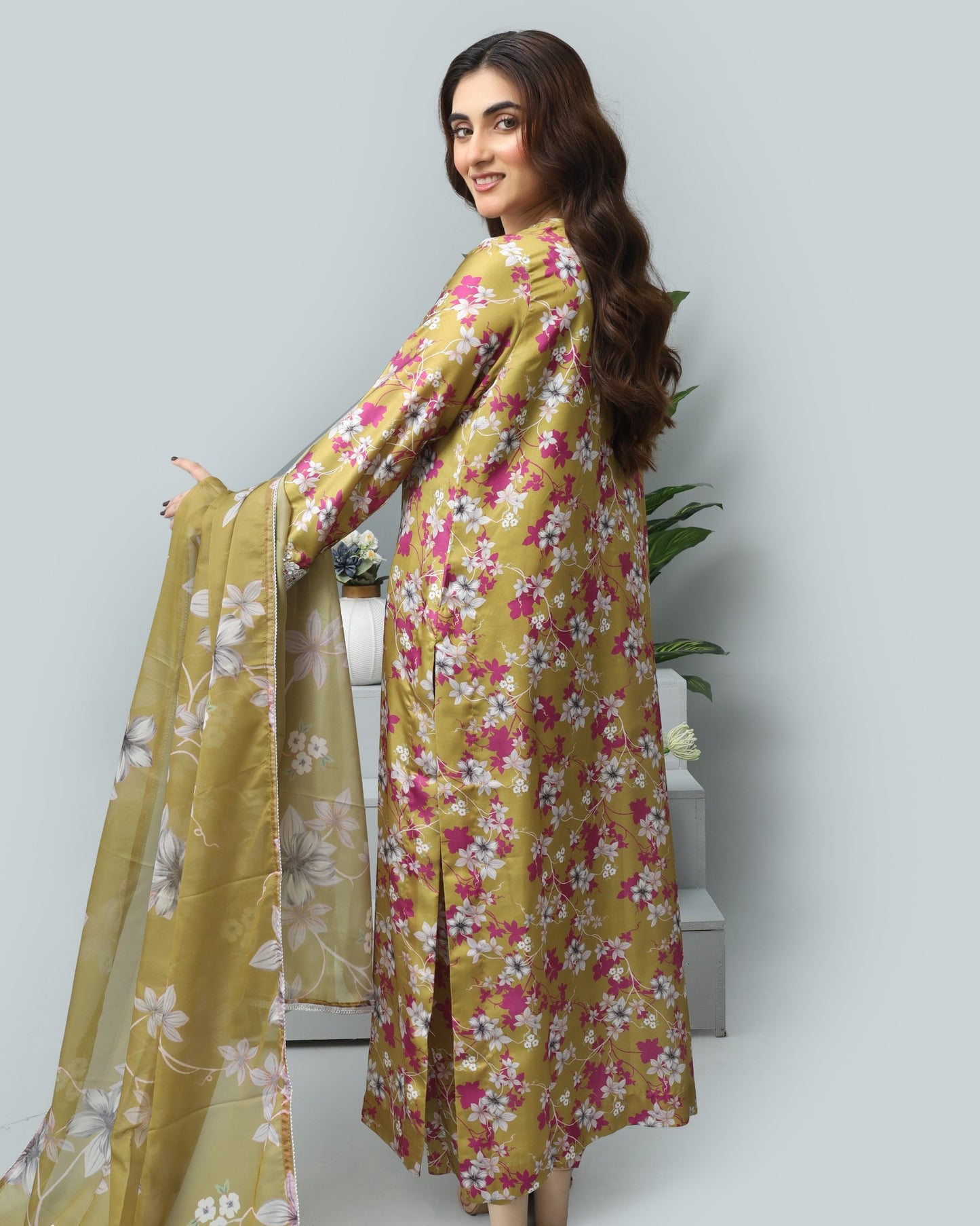 Woman wearing a floral dress with a matching dupatta on a light gray background