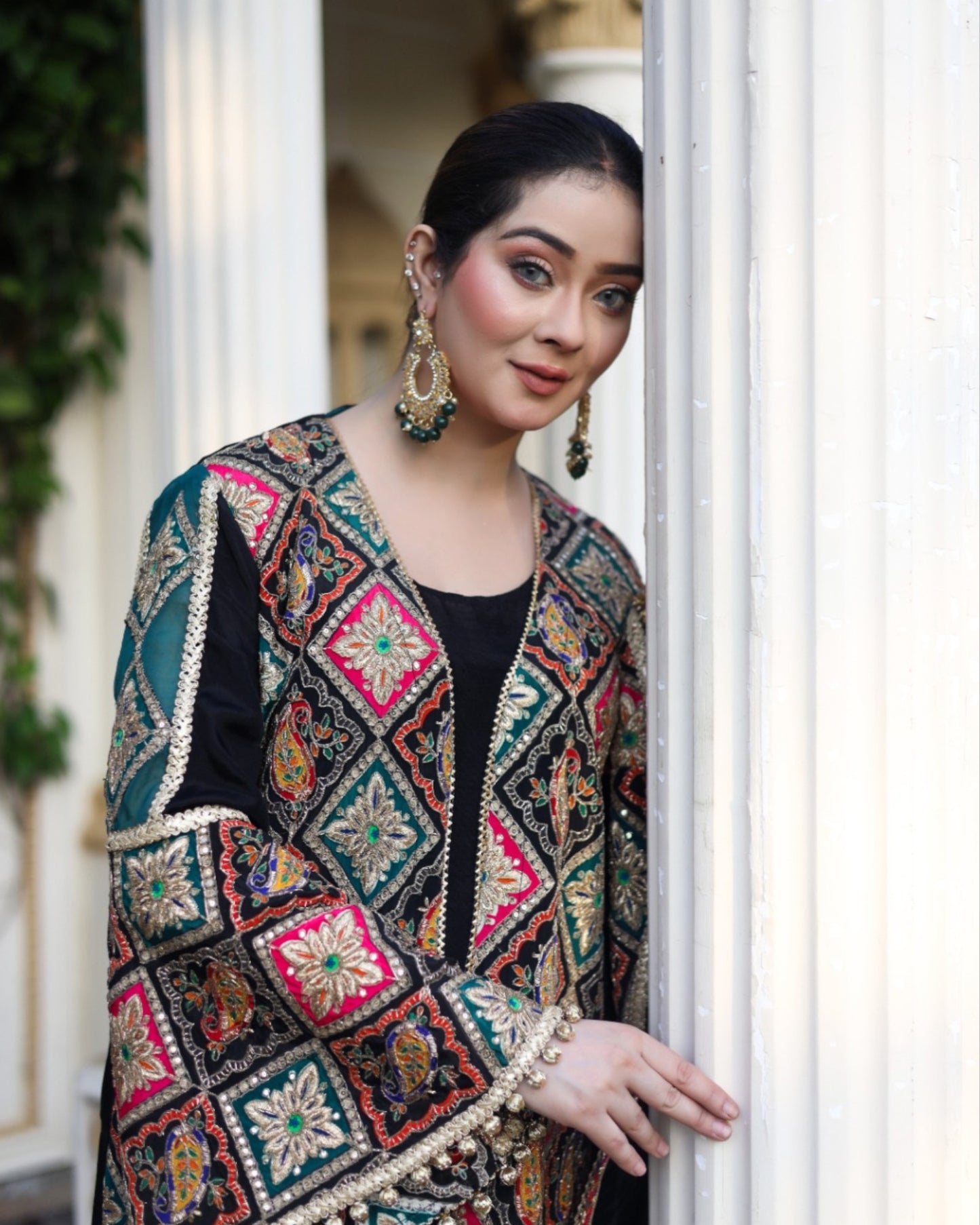 Woman wearing a colorful embroidered jacket standing indoors.